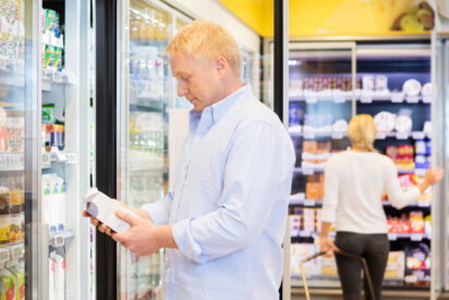 Mies pitää mehupakkausta ruokakaupassa