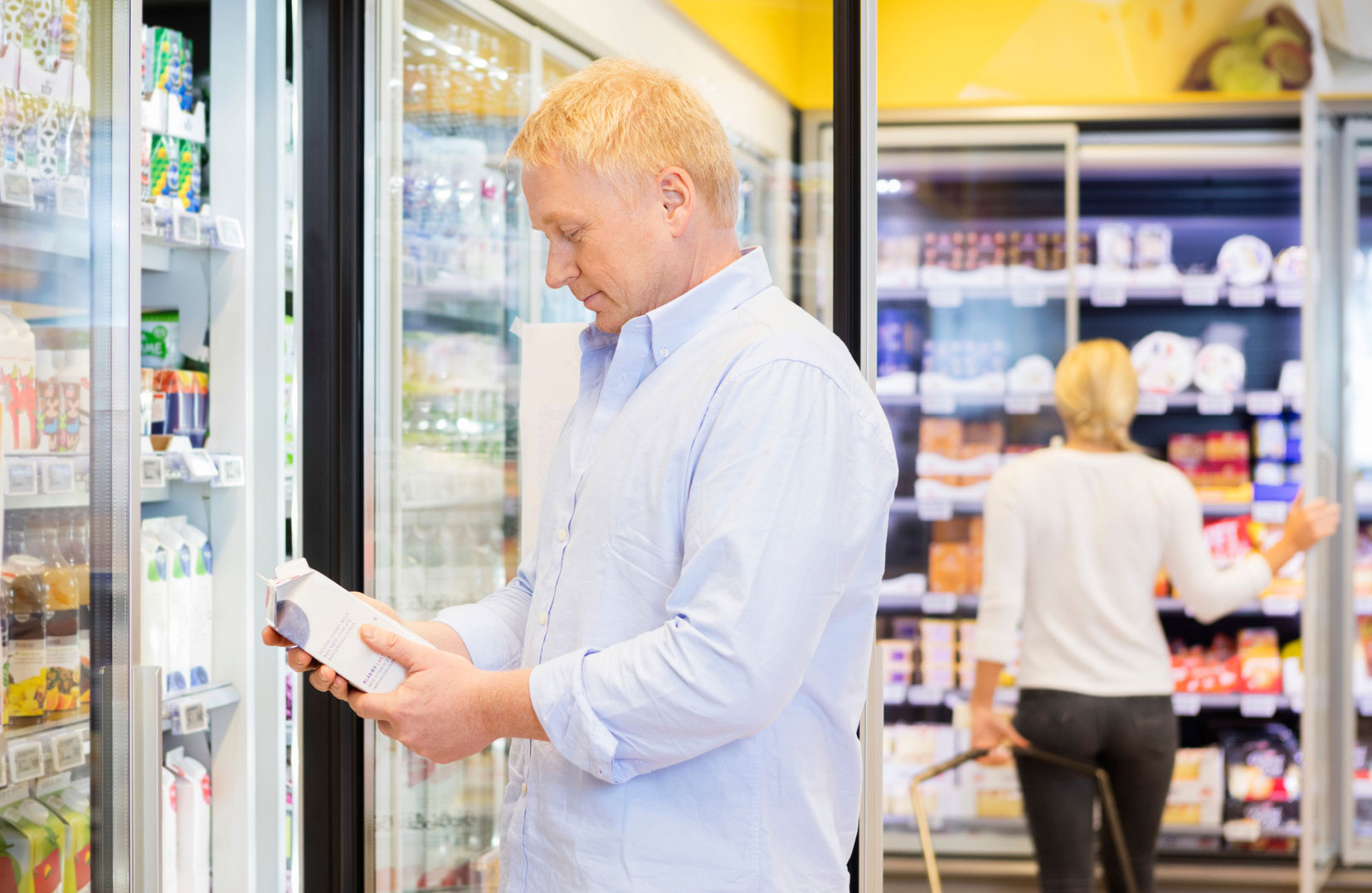 Mies pitää mehupakkausta ruokakaupassa